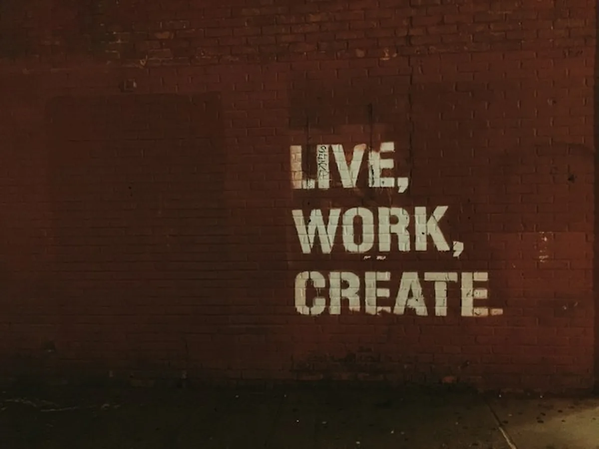 Tuğla duvara beyaz harflerle yazılmış "Live, work, create" yazısı